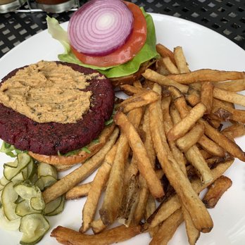Birdsall House - Beet and Quinoa Burger - A plate featuring a beet-based veggie burger with hummus topping, lettuce, tomato, onion, and pickles, accompanied by French fries. - Venues & Event Spaces Near Me - Peekskill, New York