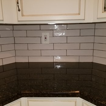 Sullivan Restoration - a kitchen with a black countertop and white cabinets - General Contractors Near Me Sullivan Restoration - a kitchen with a black countertop and white cabinets - General Contractors Near Me
