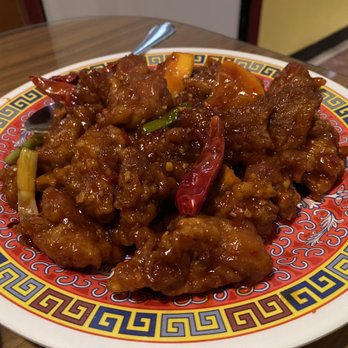 Jade Garden - Spicy orange chicken - A dish of spicy orange chicken with chili peppers, green onions, and vegetables served on a colorful Chinese-style plate. - Chinese Near Me - Tucson, Arizona