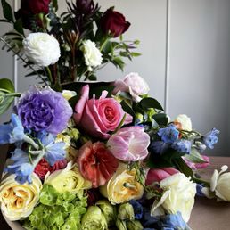 Foreground: full set of designer choice garden style bouquet in pastel. Background: part of a designer's choice garden style bouquet Foreground: full set of designer choice garden style bouquet in pastel. Background: part of a designer's choice garden style bouquet