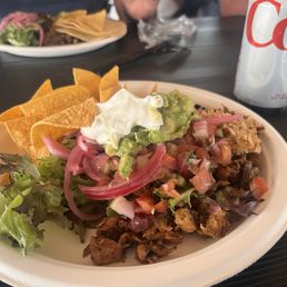 A trio of chicken, pork, and beef on top of rice and all the fixings.