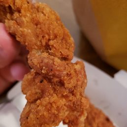a hand holding a piece of fried chicken a hand holding a piece of fried chicken