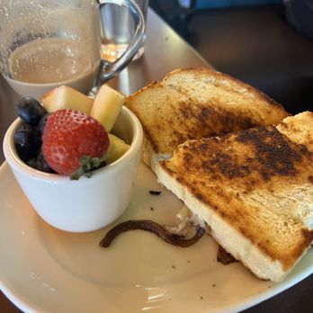 Flying Star Café - A breakfast plate featuring French toast, a small cup of mixed fresh fruit, and a coffee mug with some remaining coffee. - Bakeries Near Me - Albuquerque, New Mexico