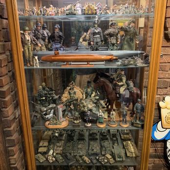 Chef Klaus' Bier Stube - G.I., Joe dolls and model tanks. - A glass display case contains military figurines, models, and vehicles, including soldiers, tanks, and aircraft, arranged on multiple shelves. - German Near Me - Frankfort, Illinois