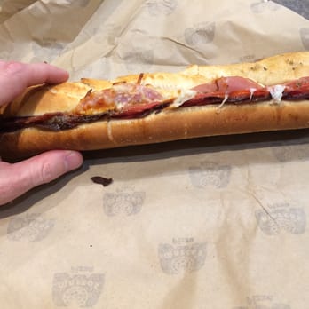 Marco's Pizza - a hand holding a sub sandwich - Pizza Near Me - Lewisville, Texas