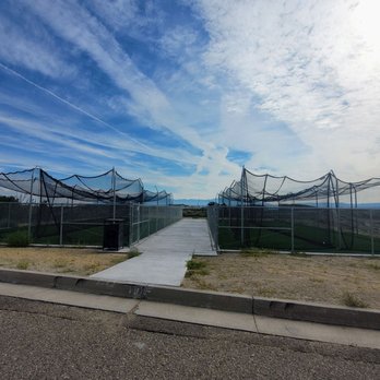 Tom Tenorio Park - Batting cages - An outdoor batting cage area enclosed by fencing, with a concrete pathway leading into the facility, set against a partly cloudy sky. - Parks Near Me - Albuquerque, New Mexico