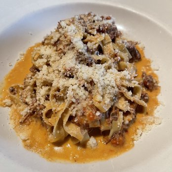 La Morra - Bolognese - so yummy! - A serving of pasta with a meat-based sauce, topped with grated cheese, served on a white plate. - Italian Near Me - Brookline, Massachusetts