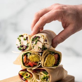 Jugo Juice - a hand grabbing a wrap from a cutting board - Juice Bars & Smoothies Near Me - Surrey, British Columbia Jugo Juice - a hand grabbing a wrap from a cutting board - Juice Bars & Smoothies Near Me - Surrey, British Columbia