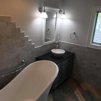 JC Builders - a bathroom with a tub, sink, and mirror - General Contractors Near Me - Janesville, Wisconsin