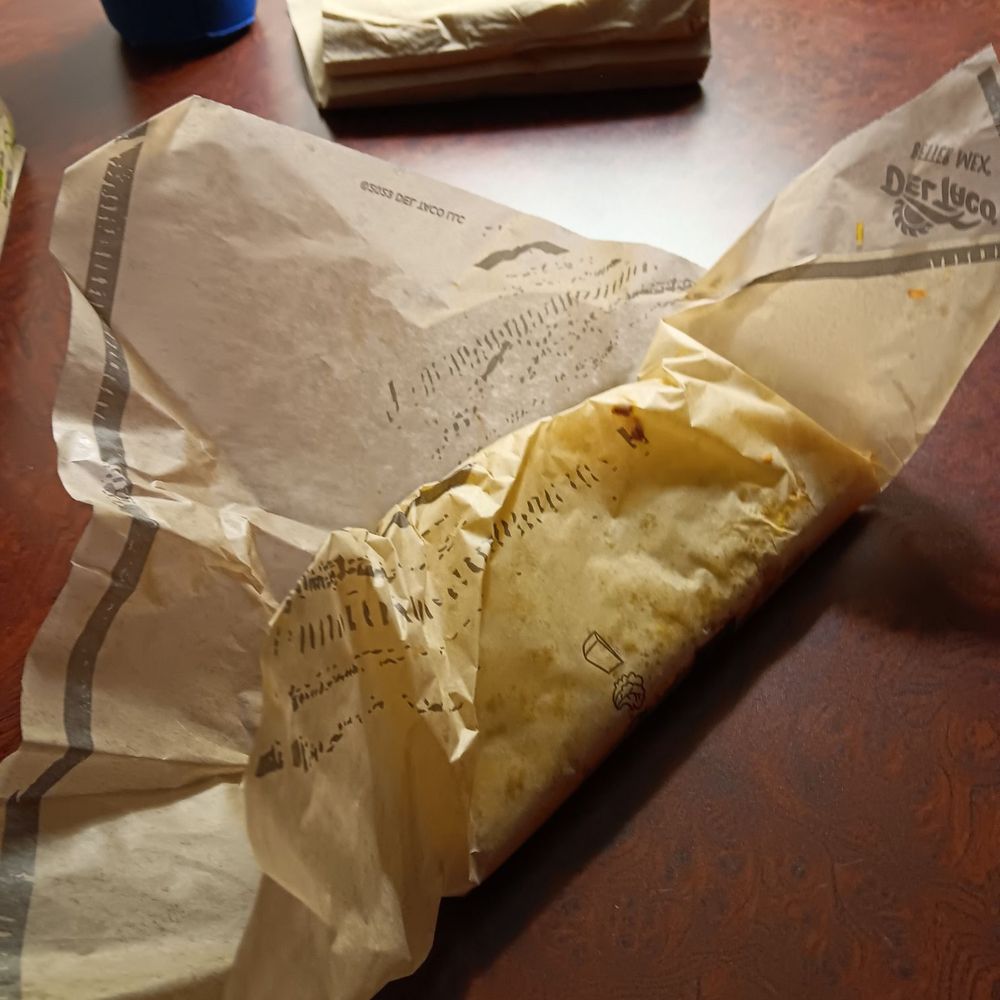 Del Taco - a burrito wrapped in paper on a table - Fast Food Near Me - Gallup, New Mexico Del Taco - a burrito wrapped in paper on a table - Fast Food Near Me - Gallup, New Mexico