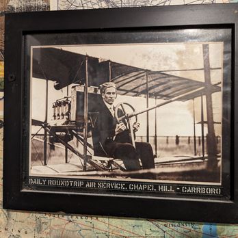 Franklin Motors - Inside one of the two unisex restrooms. I thought the caption to this photo was interesting. Roundtrip air service from where? - Beer Gardens Near Me - Chapel Hill, North Carolina