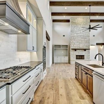 Empire Countertops - a kitchen with white cabinets and wood floors - General Contractors Near Me - Austin, Texas