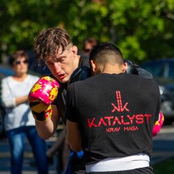 Two adult students sparring with boxing gloves during an outdoor training session.