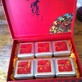 101 VE - a person opening a red box containing six square tins of tea - Health Markets Near Me - Monterey Park, California