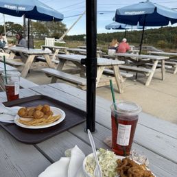 Outside picnic tables with the Cape Cod canal in the view beyond. Scallop roll and clam strip roll. Outside picnic tables with the Cape Cod canal in the view beyond. Scallop roll and clam strip roll.