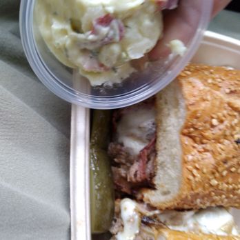 Stack'd Deli Kitchen - The image shows a food tray with various items, including a small cup of potato salad, two pickles, and a sandwich with fried chicken, lettuce, and sauce. The tray appears to be part of a casual meal setting. - Salad Near Me - Toronto, Ontario