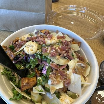 Green - A large salad bowl contains mixed greens, cheese shavings, bacon bits, and roasted vegetables, served on a wooden table. - Juice Bars & Smoothies Near Me - Wallingford, Connecticut