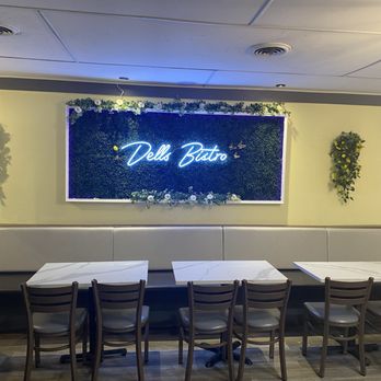 Dells Bistro - Dells Bistro - The image shows the interior of Dells Bistro with a neon sign reading 'Dells Bistro' on a decorated wall, surrounded by wall-mounted plants. - Breakfast & Brunch Near Me - Wisconsin Dells, Wisconsin