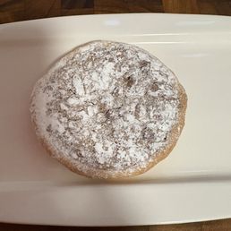 Pecan Pie Cookie - A round cookie with powdered sugar on top, placed on a white serving dish, with a wooden table background.
