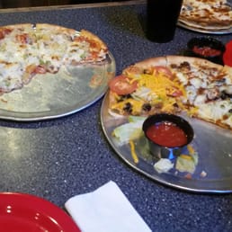 two pizzas on pans with condiments