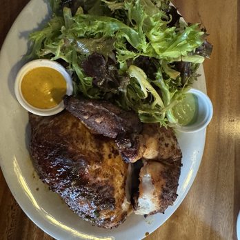 Mister Pio - Roasted chicken served with fresh mixed greens salad, two sauces in small cups, on an oval white plate. - Peruvian Near Me - Phoenix, Arizona