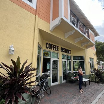 Coffee District - a woman standing in front of a coffee shop - Coffee & Tea Near Me - Delray Beach, Florida