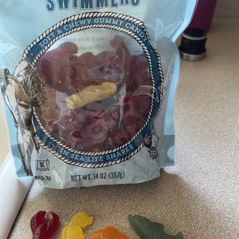 Trader Joe's - A new fav! Scandinavian Swimmers are like Swedish fish only softer and better tasting. And so cute!! - A bag of Trader Joe's Scandinavian Swimmers gummy candies is shown with four candies on a surface, including a red, yellow, orange, and green gummy. - Grocery Near Me - Eugene, Oregon