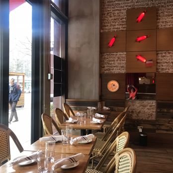 Amelie - A restaurant interior features wooden wall panels, red fish wall decorations, and a large window showing pedestrians outside. - Wine Bars Near Me - Washington, DC, District of Columbia