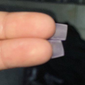 Future Nails - The image shows a close-up of fingers with purple nail polish applied to the tips, which are square-shaped. The fingers are positioned horizontally, and the background appears to be a dark surface, possibly clothing or a fabric. The focus is on the nails and fingers, with details of the skin and nail polish visible. - Nail Salons Near Me - Chicago, Illinois