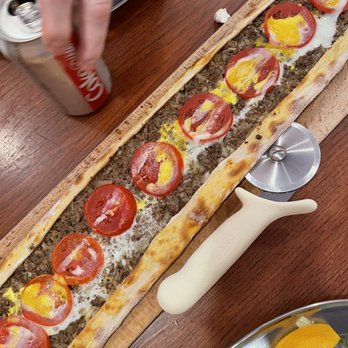 Pide 28 - a person putting toppings on a pizza - Turkish Near Me - Paterson, New Jersey
