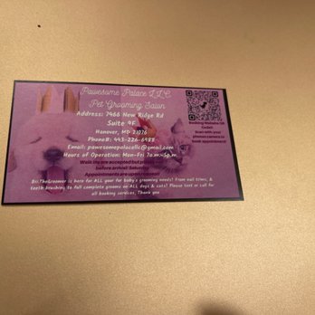 Pawesome Palace - Business Card with QR code for booking grooming services - The image shows a business card for Pawesome Palace LLC pet grooming salon, placed on a beige surface. The card has a purple background with a picture of a white cat with blue eyes. It includes contact information such as address, phone number, email, and hours of operation. A QR code is present in the top right corner, with instructions to scan for booking appointments. The card also mentions services like nail trims, full grooming, and vegan pet coloring. - Pet Groomers Near Me - Hanover, Maryland