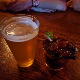 a woman sitting at a table with a glass of beer a woman sitting at a table with a glass of beer