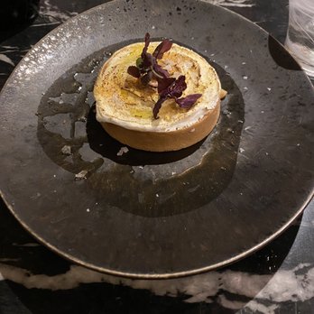 Sakaba - Yuzu tart. - A yuzu tart with a creamy topping, garnished with microgreens, served on a dark, textured plate at a restaurant. - Sushi Bars Near Me - Avon, Colorado