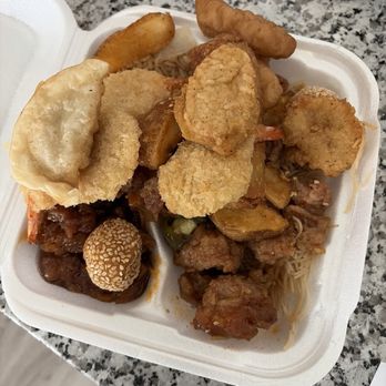 Buffet King - Bunch of things - A foam takeout container holds fried chicken pieces, fried fish fillets, potato wedges, and rice, placed on a granite countertop. - Chinese Near Me - Austin, Texas