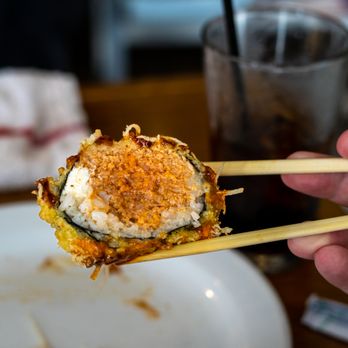Tomo - a person holding chopsticks over a plate of food - Sushi Bars Near Me - New Albany, Indiana Tomo - a person holding chopsticks over a plate of food - Sushi Bars Near Me - New Albany, Indiana