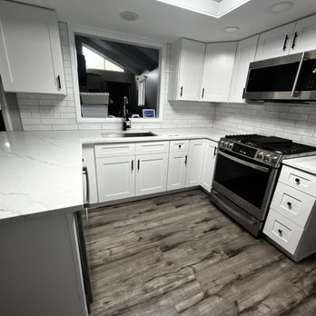 Independent Remodeling - All Done - A kitchen featuring white cabinetry, a marble-patterned countertop, stainless steel microwave and stove, and wood-style flooring. - General Contractors Near Me - Bloomingdale, Illinois