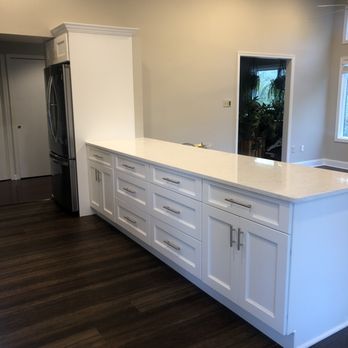 FJ Contractors - a kitchen with white cabinets and wood floors - General Contractors Near Me