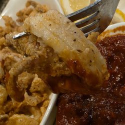 Close-up of a fork dipping one of the Calamari rings into the sauce.