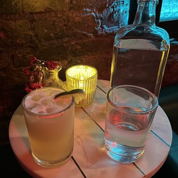 Stickett Inn - a table with a drink and a bottle - Bars Near Me - New York, New York Stickett Inn - a table with a drink and a bottle - Bars Near Me - New York, New York