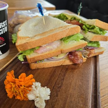 Con Azucar Cafe - Club sandwich plated on a cutting board with pretty flowers - Coffee & Tea Near Me - San Jose, California Con Azucar Cafe - Club sandwich plated on a cutting board with pretty flowers - Coffee & Tea Near Me - San Jose, California