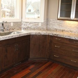 Adriano Granite and Quartz - Kitchen cornering granite and sink with stone backsplash.
