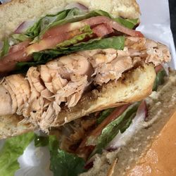 Flava House - Slapping Salmon Sandwich Blackened Salmon on Brioche Bun, Lettuce, Tomato, Red Onion, and Cilantro Lime Aioli