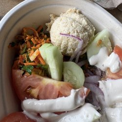 Close-up of the fresh vegetables in the rice bowl with steak. There is the Mediterranean carrot salad and the hummus as well.