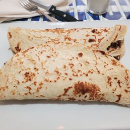 Baleadas La Express Supreme - Two folded burritos with toasted tortillas are placed on a white plate, with a fork and knife on a table setting.
