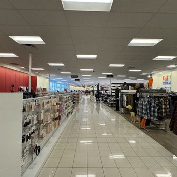 Kohl’s - A wide aisle inside a retail store features clothing racks on the right and household items on the left, with shoppers in the distance. - Outlet Stores Near Me - Katy, Texas