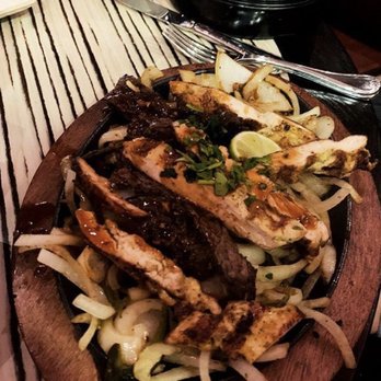 Temazcal Tequila Cantina - Chicken and steak fajitas on top of grilled onions. Side of salsa, bean dip, and Mexican rice not pictured - Mexican Near Me - Dedham, Massachusetts