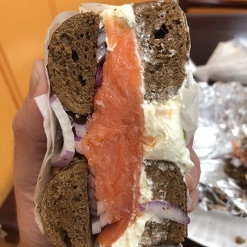 Highridge Bagels - a hand holding a sandwich with salmon and onions - Bagels Near Me - Hartsdale, New York Highridge Bagels - a hand holding a sandwich with salmon and onions - Bagels Near Me - Hartsdale, New York