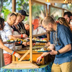 Voyagers of the Pacific Luau - Luau guests gathered around buffet table capturing the lively and communal spirit of a traditional luau at the Voyagers of the Pacific