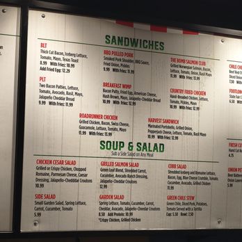 Laguna Burger - Nov 2025 - A menu board from a casual restaurant offers a selection of sandwiches, salads, and soups. Sandwich options include BLT, BBQ Pulled Pork, Breakfast Wimp, Roadrunner Chicken, The Bomb Salmon Club, Country Fried Chicken, and Harvest Sandwich, each with detailed ingredients and prices. Salads include Chicken Cesar, Grilled Salmon, Cobb, Side Salad, Garden, and Green Chile Stew, with descriptions of ingredients and prices. The board is organized into sections with clear headings and is designed for easy reading. - Burgers Near Me - Albuquerque, New Mexico