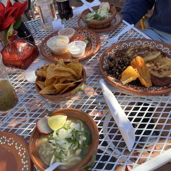 Gobble This - Pozole and pupusas! - An outdoor table features Salvadoran pupusas, Mexican tacos, chips, salsa, and drinks including soda and water. - Salvadoran Near Me - Albuquerque, New Mexico